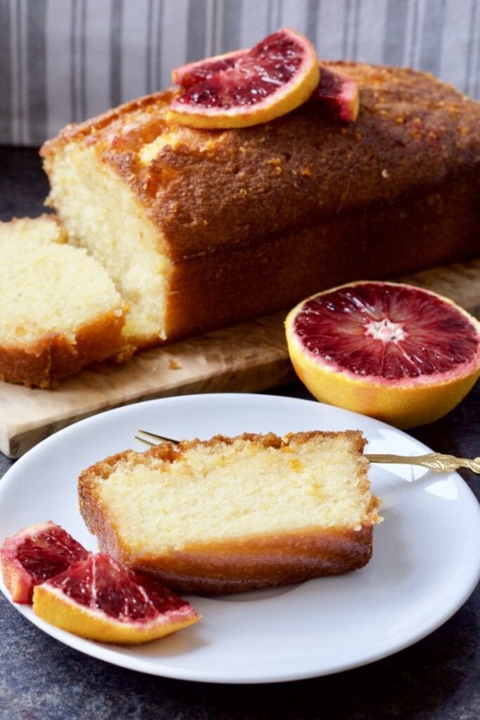 Slice of cake on a plate and loaf in the background.