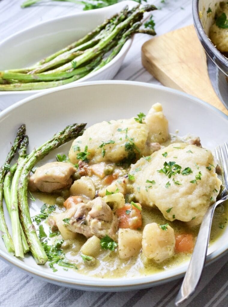 Wild Garlic Chicken Stew with Cheesy Dumplings on a plate with asparagus